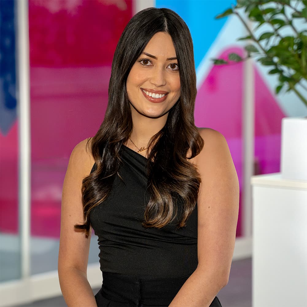 Photo of Alice Hoy, Commercial Customer Service Team Leader at Utilita Business, sat in front of colourful glass panels.
