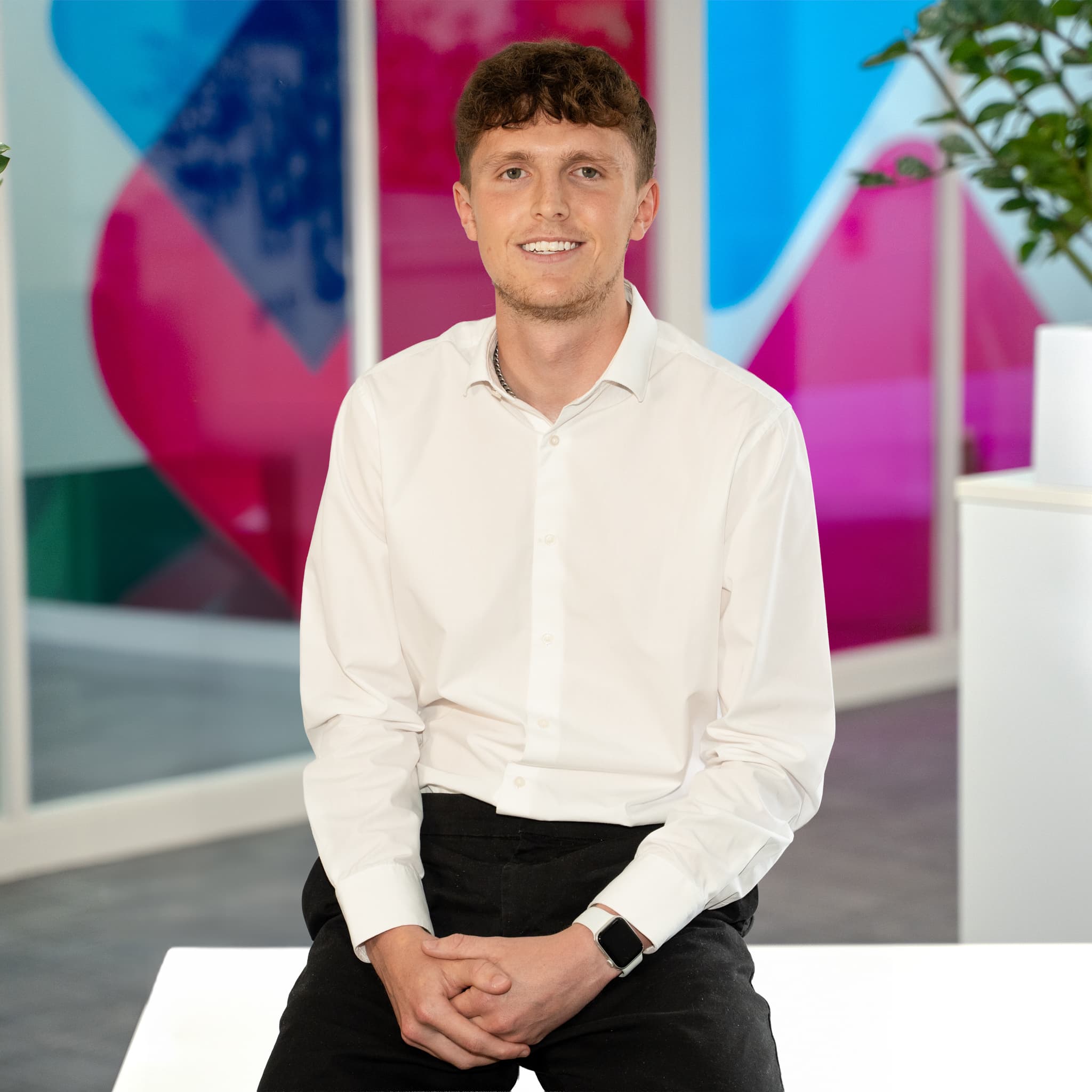 Photo of Ben McInnes, Commercial Sales Executive at Utilita Business, sat in front of colourful glass panels.