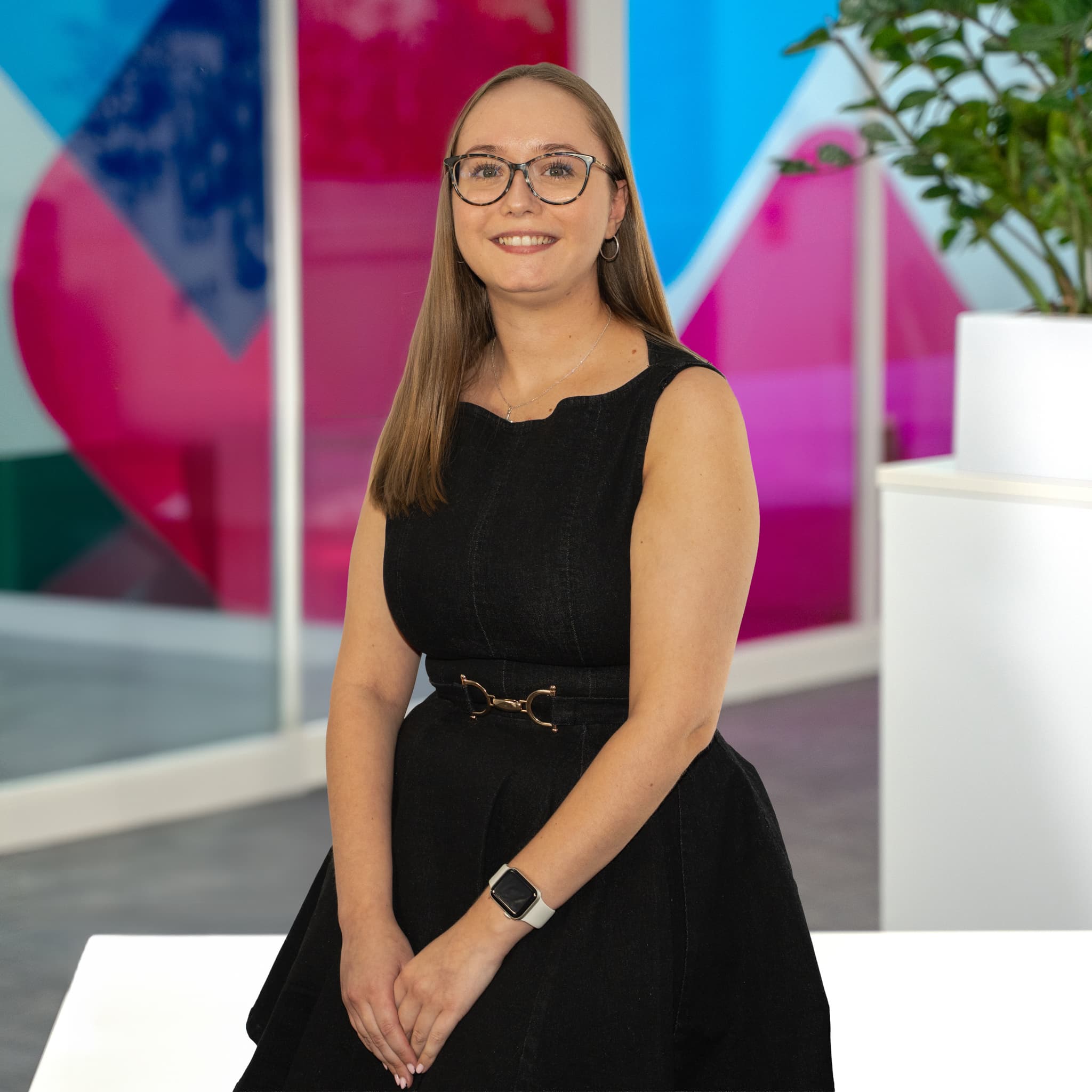 Photo of Caitlin Green, Commercial Sales Executive at Utilita Business, sat in front of colourful glass panels.