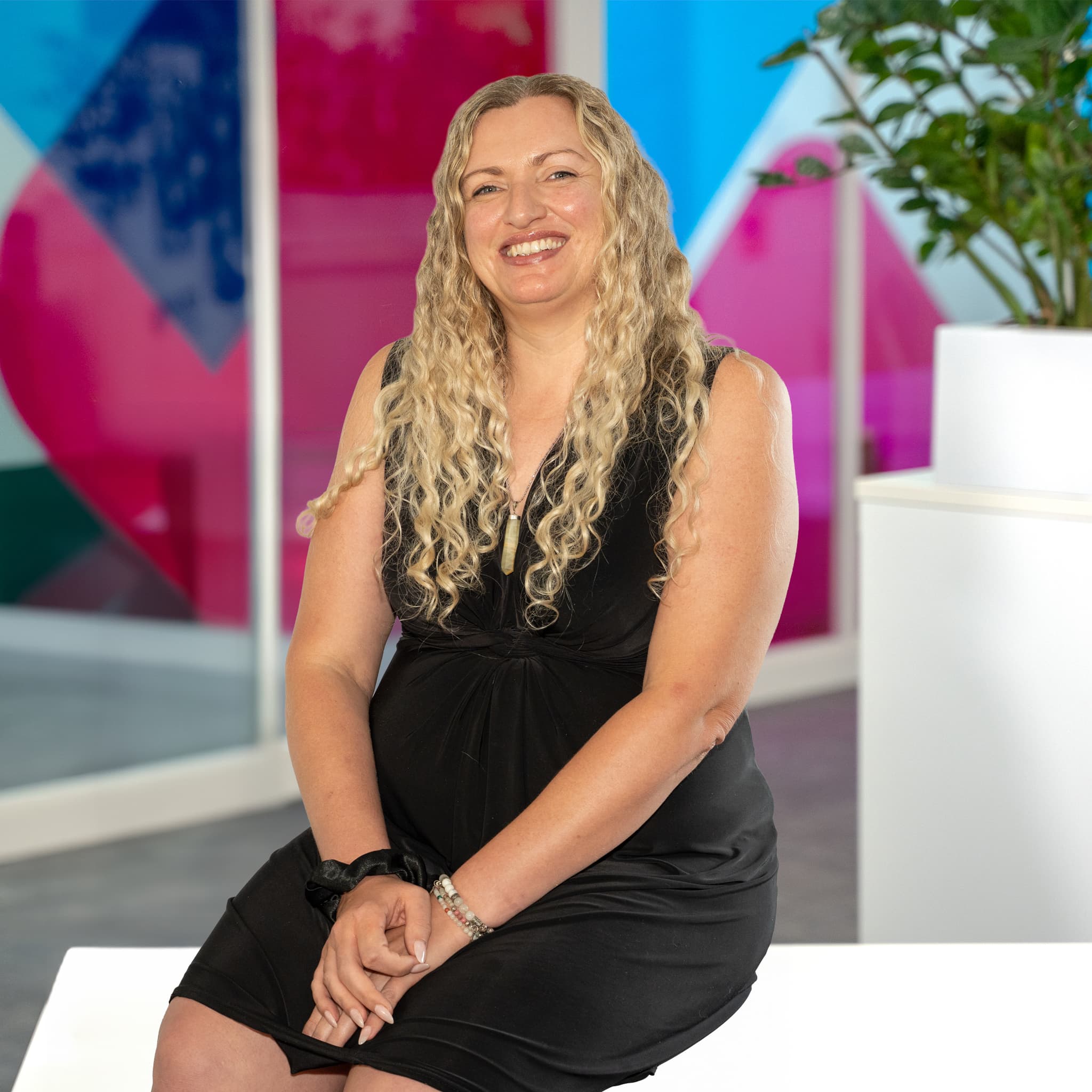 Photo of Lavinia Crosby, Commercial Retentions Executive at Utilita Business, sat in front of colourful glass panels.