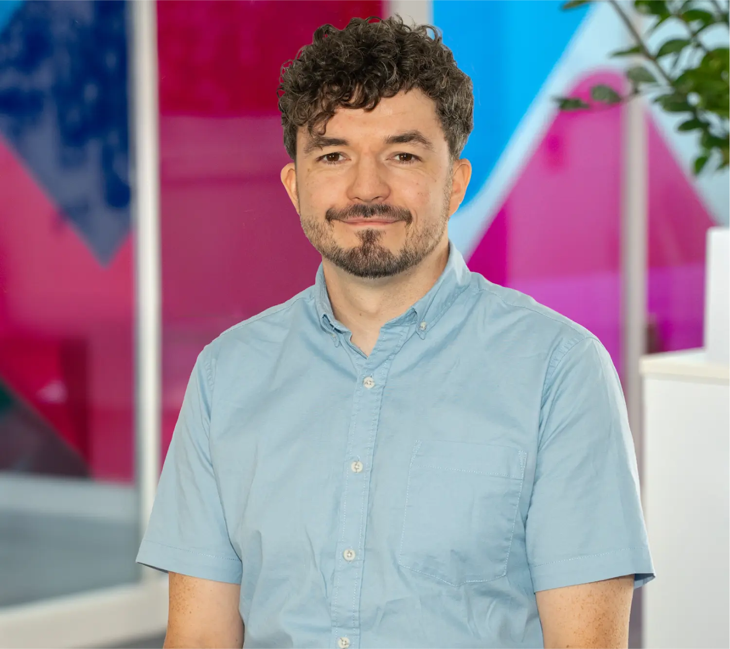 Photo of Andrew Flynn, Commercial Sales Mentor at Utilita Business, sat in front of colourful glass panels.